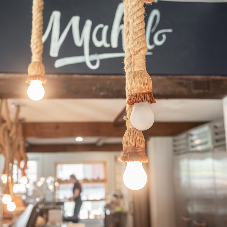 Rope-wrapped pendant lights glow inside a warmly lit restaurant beneath a chalkboard sign.
